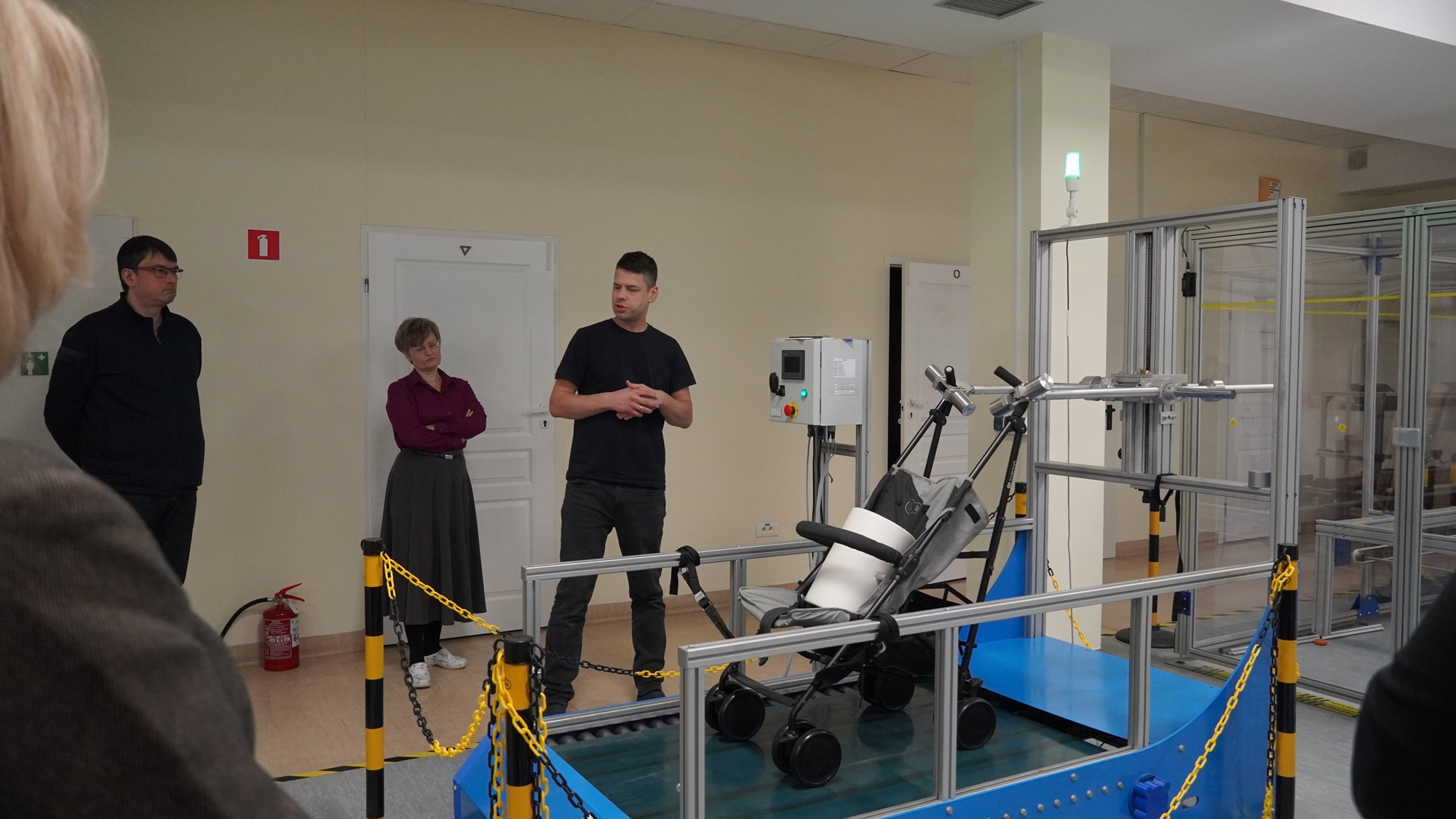 Unieruchomiony wózek dziecięcy na bieżni elektrycznej, wokół uczestnicy spotkania.